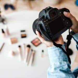 Unrecognizable Female Photographer Taking Photo Of Cosmetic Products Indoor, Cropped